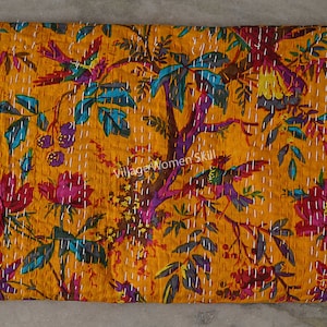 May include: A yellow kantha quilt with a floral and bird pattern. The quilt is hand-stitched and features a variety of colors, including pink, blue, green, and purple. The quilt is made of cotton and is perfect for adding a touch of bohemian style to your home.