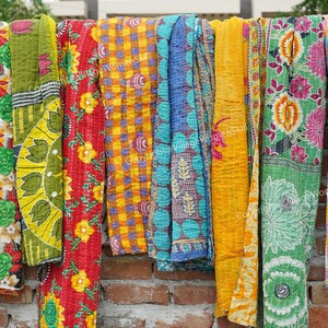 Puede incluir: Una colecci&oacute;n de colchas kantha coloridas colgadas en una pared de ladrillo. Las colchas est&aacute;n hechas de saris reciclados y presentan una variedad de patrones florales y geom&eacute;tricos.