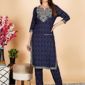 May include: A navy blue and gold patterned kurta and palazzo set. The kurta has a V-neckline and gold embroidery around the neckline. The palazzo pants have a wide leg and a gold trim around the bottom.