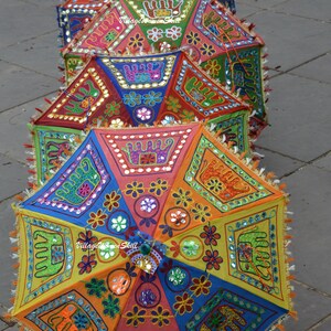 May include: A stack of colourful, hand-stitched umbrellas with intricate embroidery and mirror embellishments. The umbrellas are decorated with elephants, flowers, and geometric patterns.