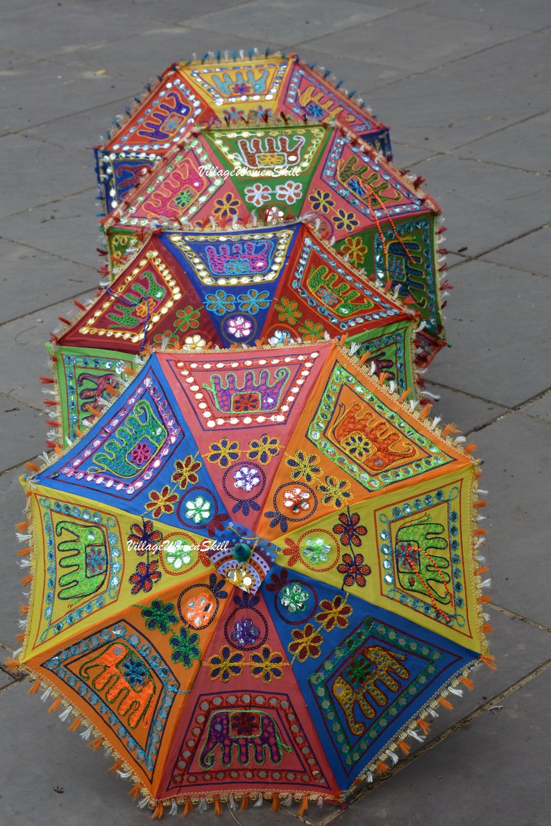May include: A stack of colourful, hand-stitched umbrellas with intricate embroidery and mirror embellishments. The umbrellas are decorated with elephants, flowers, and geometric patterns.