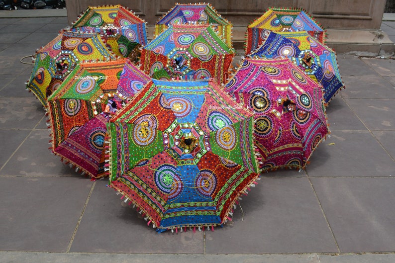 Puede incluir: Una colecci&oacute;n de paraguas coloridos y estampados con dise&ntilde;os intrincados y adornos. Los paraguas est&aacute;n hechos de tela y tienen una variedad de colores, incluyendo rojo, azul, verde, amarillo y rosa. Los paraguas est&aacute;n decorados con lentejuelas, cuentas y otros adornos.