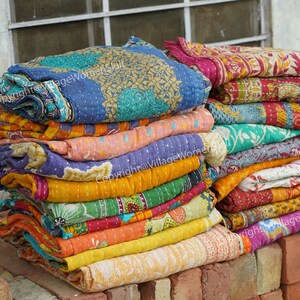 Puede incluir: Una pila de colchas kantha coloridas, hechas de saris reciclados, con intrincados patrones y costuras. Copyright@VillageWomenSkill