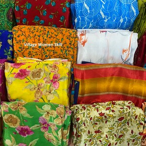 May include: A collection of colorful fabric swatches with floral and geometric patterns. The swatches are arranged in a stack and include a variety of colors, including red, blue, green, yellow, and orange. The text "Village Women Skill" is visible on one of the swatches.