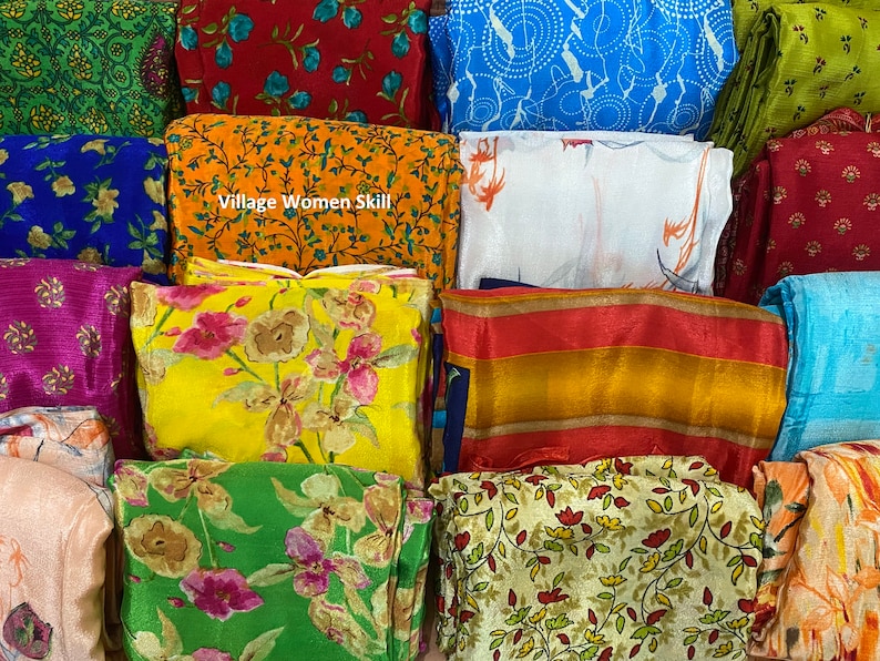 May include: A collection of colorful fabric swatches with floral and geometric patterns. The swatches are arranged in a stack and include a variety of colors, including red, blue, green, yellow, and orange. The text "Village Women Skill" is visible on one of the swatches.