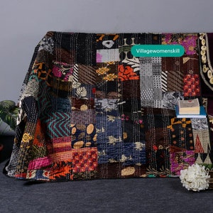 May include: A black and multi-colored patchwork quilt with a variety of patterns and textures. The quilt is made of recycled saris and is hand-stitched. The quilt is called "Villagewomenskill".