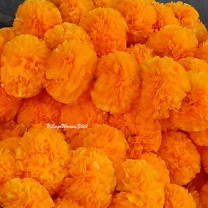 Puede incluir: Primer plano de un montón de flores de caléndula de color naranja brillante. Las flores están hechas de papel y están dispuestas en un patrón aleatorio. Las flores son todas del mismo tamaño y forma.