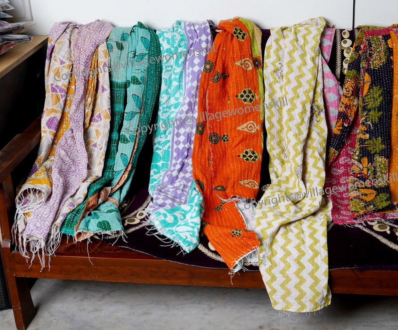 Może przedstawiać: Kolekcja kolorowych kołder kantha z r&oacute;żnymi wzorami, w tym kwiatowymi, geometrycznymi i paisley. Kołdry są wykonane z recyklingowanych sari i są szyte ręcznie. Copyright @villagewomenskill
