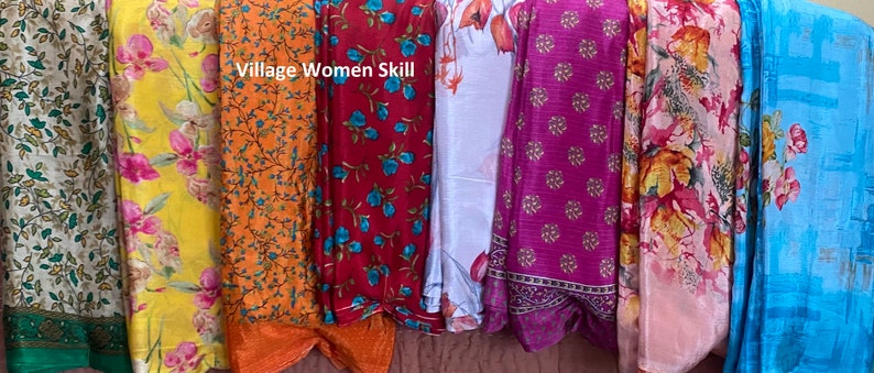 May include: A collection of eight colorful fabric scarves with floral patterns. The scarves are arranged vertically and have a variety of colors, including yellow, orange, red, blue, white, pink, and light blue. The text "Village Women Skill" is visible at the top of the image.