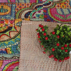 Puede incluir: Una colcha de retazos colorida con un patr&oacute;n floral. La colcha est&aacute; hecha de diferentes telas y est&aacute; cosida con una puntada corrida. La colcha est&aacute; colocada sobre una superficie beige con una peque&ntilde;a planta en maceta en la esquina.