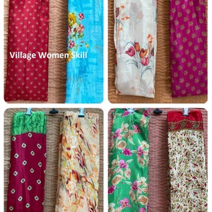 May include: Six different colorful scarves with floral patterns. The scarves are hanging on a clothesline. The text "Village Women Skill" is visible on the top left scarf.