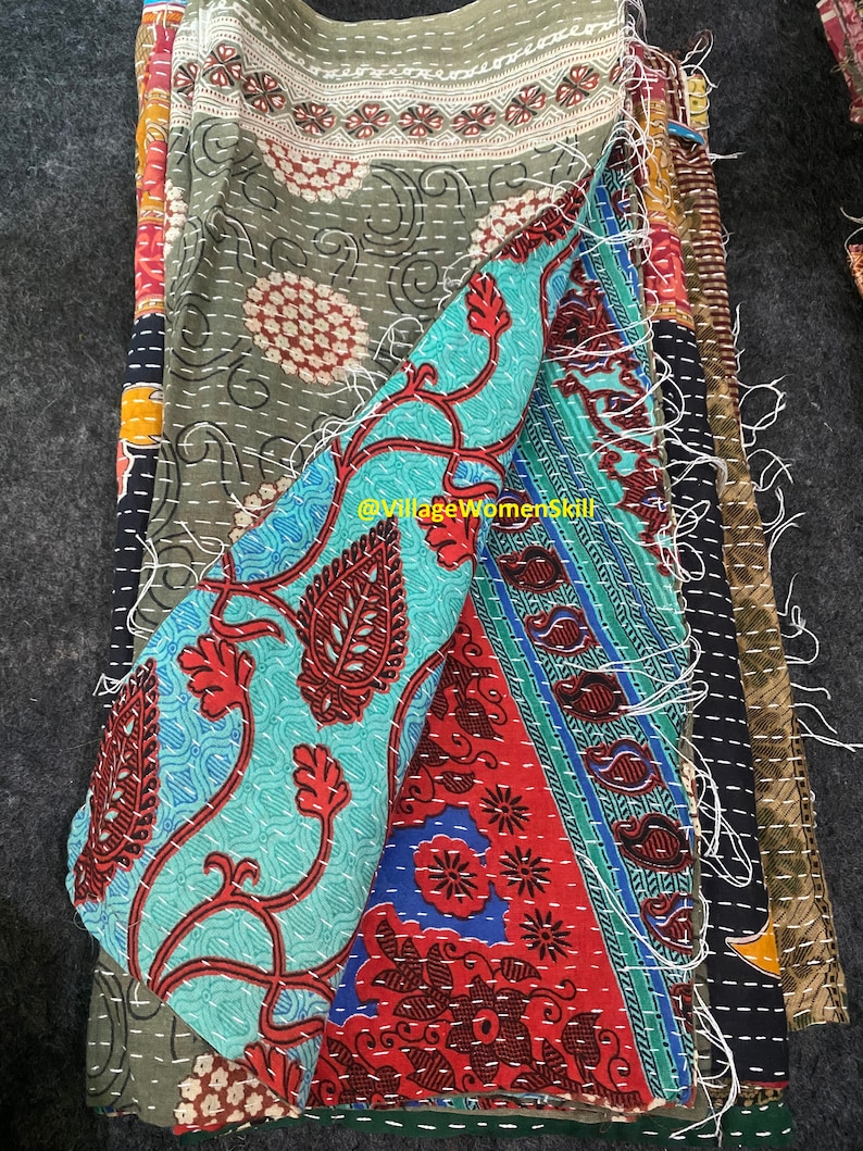 May include: A stack of colorful fabric squares with intricate patterns, stitched together with white thread. The fabric is a mix of green, blue, red, and black. The fabric is frayed at the edges, giving it a vintage look.  @VillageWomensSkill