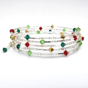 May include: A spiral wrap bracelet with clear beads and colorful accents. The bracelet features red, green, and gold-colored faceted beads. The bracelet is made of thin, clear, flexible wire and is designed to wrap around the wrist.