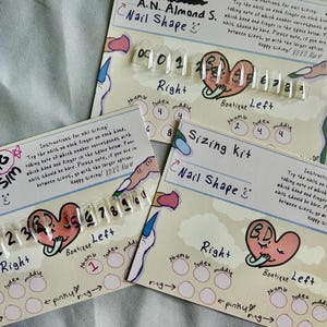 Puede incluir: Kits de tallas de uñas con muestras de uñas acrílicas transparentes. Cada kit presenta un gráfico en forma de corazón y texto que indica la forma de la uña e instrucciones de tallas. Los kits están dispuestos sobre una superficie azul claro.