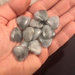 May include: A collection of heart-shaped labradorite stones in various shades of gray and white. The stones are smooth and polished, with a subtle shimmer.