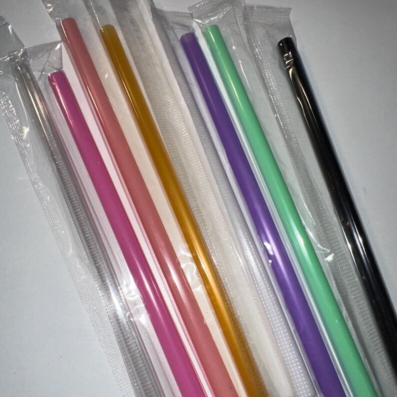 May include: An assortment of colorful reusable straws in individual clear plastic packaging. The straws are in various colors, including pink, orange, purple, and green. There is also a silver and a black straw. The straws are straight and cylindrical.