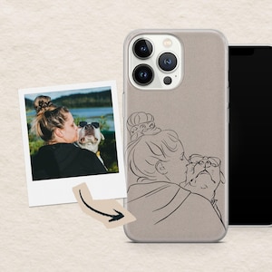 Può includere: Custodia per telefono marrone chiaro con un disegno a tratto di una persona che bacia un cane. Un bordo trasparente circonda la custodia. È visibile anche una foto polaroid di una persona che bacia un cane con gli occhiali da sole.