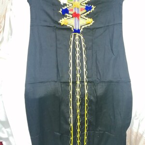 May include: A black long-sleeved dress with a colorful embroidered design on the neckline. The embroidery features geometric shapes, tassels, and pom-poms in shades of blue, red, green, and yellow. The dress has a long, flowing skirt and a fitted bodice.