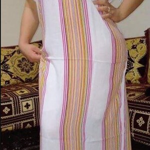 May include: A white and multi-colored striped long-sleeved dress with a white crocheted design on the neckline.