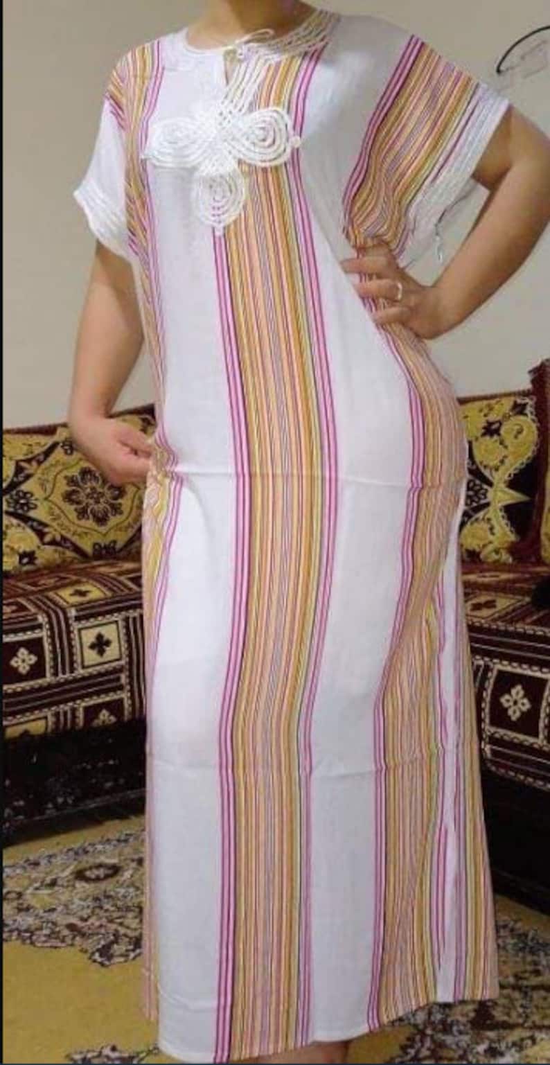 May include: A white and multi-colored striped long-sleeved dress with a white crocheted design on the neckline.