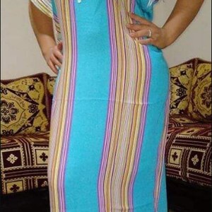 May include: A long, blue and white striped dress with a white crocheted design on the front. The dress has a loose fit and is made of a lightweight fabric.