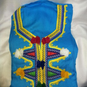 May include: A blue garment with intricate gold embroidery and colorful tassels. The embroidery features a geometric pattern with a central V-shape.