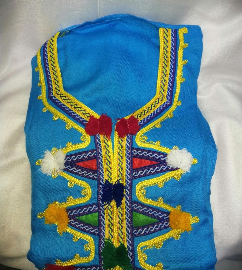 May include: A blue garment with intricate gold embroidery and colorful tassels. The embroidery features a geometric pattern with a central V-shape.