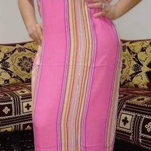 May include: A pink and white striped dress with a white crocheted design on the neckline. The dress has short sleeves and a long, flowing skirt.