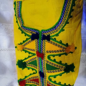 May include: Yellow fabric top with colorful embroidery and pom-poms. The embroidery features geometric shapes and a variety of colors, including red, green, blue, and yellow.