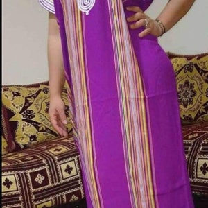 May include: A long, purple and white striped dress with a white crocheted design on the neckline. The dress has short sleeves and a loose fit.