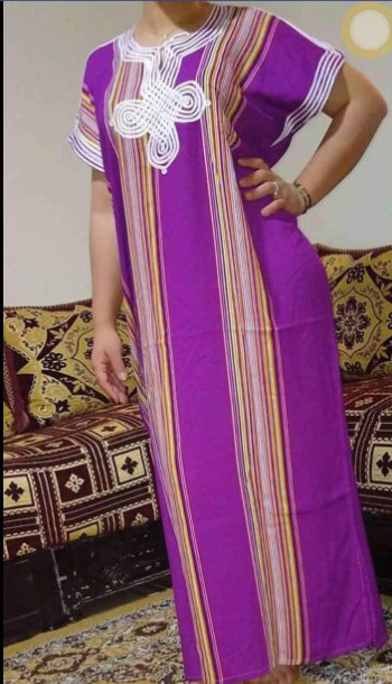 May include: A long, purple and white striped dress with a white crocheted design on the neckline. The dress has short sleeves and a loose fit.