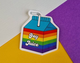 May include: A white sticker with a rainbow design and the text "Gay Juice" in a retro font. The sticker is shaped like a carton of juice with a straw.