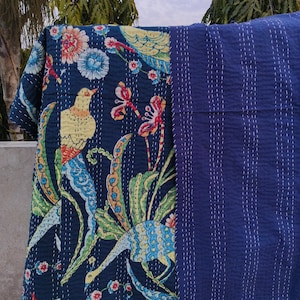 May include: A kantha quilt with a dark blue background featuring a colorful floral and bird design. The quilt is reversible with a solid dark blue side.