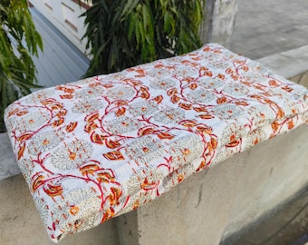 Puede incluir: Tela de algodón blanca con estampado floral rojo y naranja. La tela está doblada por la mitad y tiene una superficie texturizada.