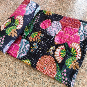 May include: A black kantha quilt with a floral pattern in shades of pink, green, and brown. The quilt is made of cotton and is hand-stitched.