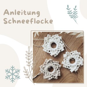 Puede incluir: Tres copos de nieve de macramé blancos sobre una superficie de madera. Los copos de nieve están hechos con un cordón blanco grueso y tienen un agujero circular en el centro. El texto "Anleitung Schneeflocke" es visible en la parte superior de la imagen.