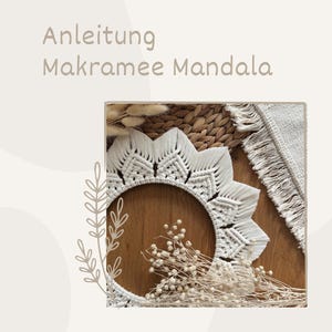 Puede incluir: Un mandala de macramé blanco con un diseño geométrico, exhibido sobre una superficie de madera. La imagen incluye el texto "Anleitung Makramee Mandala". Flores secas y texturas tejidas complementan la obra de arte artesanal.