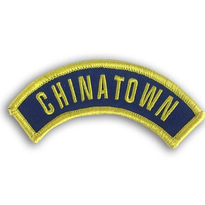 May include: A blue and gold embroidered patch with the word "CHINATOWN" in yellow lettering.
