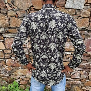 Pu&ograve; includere: Una camicia nera a maniche lunghe con un motivo floreale bianco. La camicia ha un colletto abbottonato e una vestibilit&agrave; rilassata.