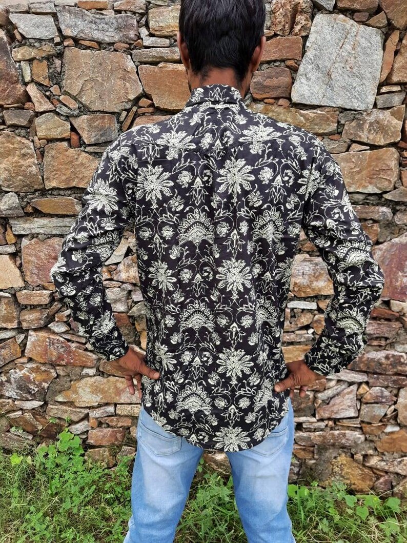 Pu&ograve; includere: Una camicia nera a maniche lunghe con un motivo floreale bianco. La camicia ha un colletto abbottonato e una vestibilit&agrave; rilassata.