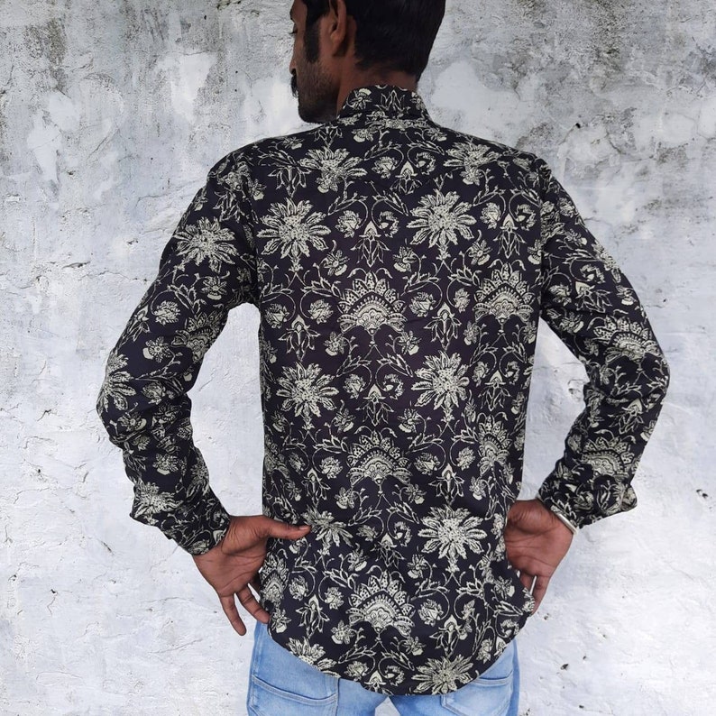 Pu&ograve; includere: Una camicia nera a maniche lunghe con un motivo floreale bianco. La camicia ha un colletto alla coreana e una chiusura con bottoni sul davanti.