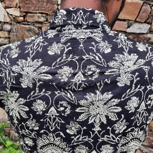 Pu&ograve; includere: Una camicia a stampa floreale bianca e nera con colletto abbottonato. La camicia presenta un design tradizionale indiano con dettagli intricati.