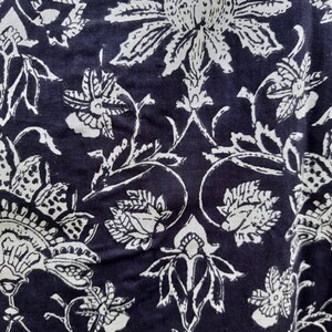 Pu&ograve; includere: Tessuto nero con un motivo floreale bianco. Il motivo presenta disegni intricati di fiori e foglie.