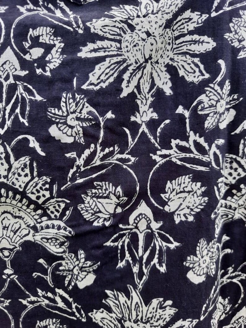 Pu&ograve; includere: Tessuto nero con un motivo floreale bianco. Il motivo presenta disegni intricati di fiori e foglie.