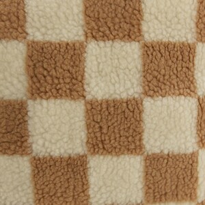 May include: Close-up of a checkered fabric with brown and white squares. The fabric has a soft, fuzzy texture.