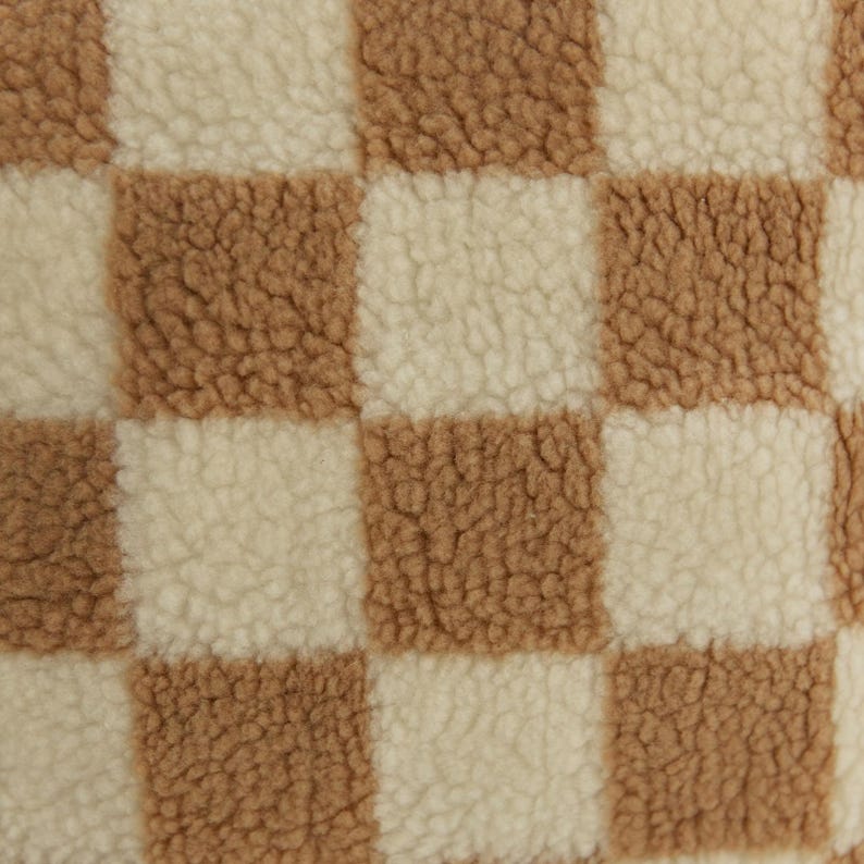 May include: Close-up of a checkered fabric with brown and white squares. The fabric has a soft, fuzzy texture.