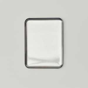 May include: A rectangular, brushed metal object with rounded corners. The metal has a reflective surface, and the edges are outlined with a darker, possibly black, border. The object is set against a plain, light gray background.