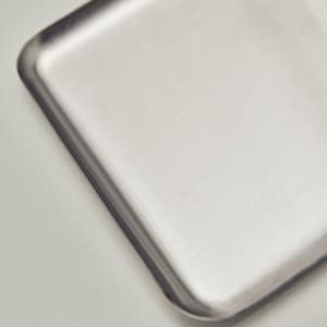 May include: A close-up of a rectangular, brushed metal tray with rounded corners. The tray has a silver finish and a slightly textured surface. The edges are darker than the center, creating a subtle contrast.