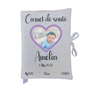 Peut inclure: Un carnet de santé blanc pour bébé avec un cadre en forme de cœur violet autour d'une photo d'une petite fille. Le carnet porte le texte "Carnet de santé" et le nom du bébé "Amelia" avec la date "6 Mai 2022". Le carnet indique également le poids du bébé "3kg 420", la taille "50cm" et la longueur "06cm18" imprimés en bas.