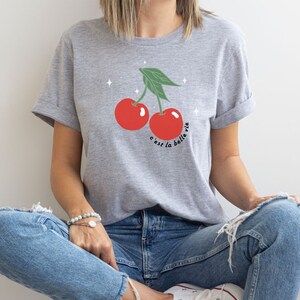 May include: A gray t-shirt with a graphic of two red cherries and the text "c'est la belle vie".